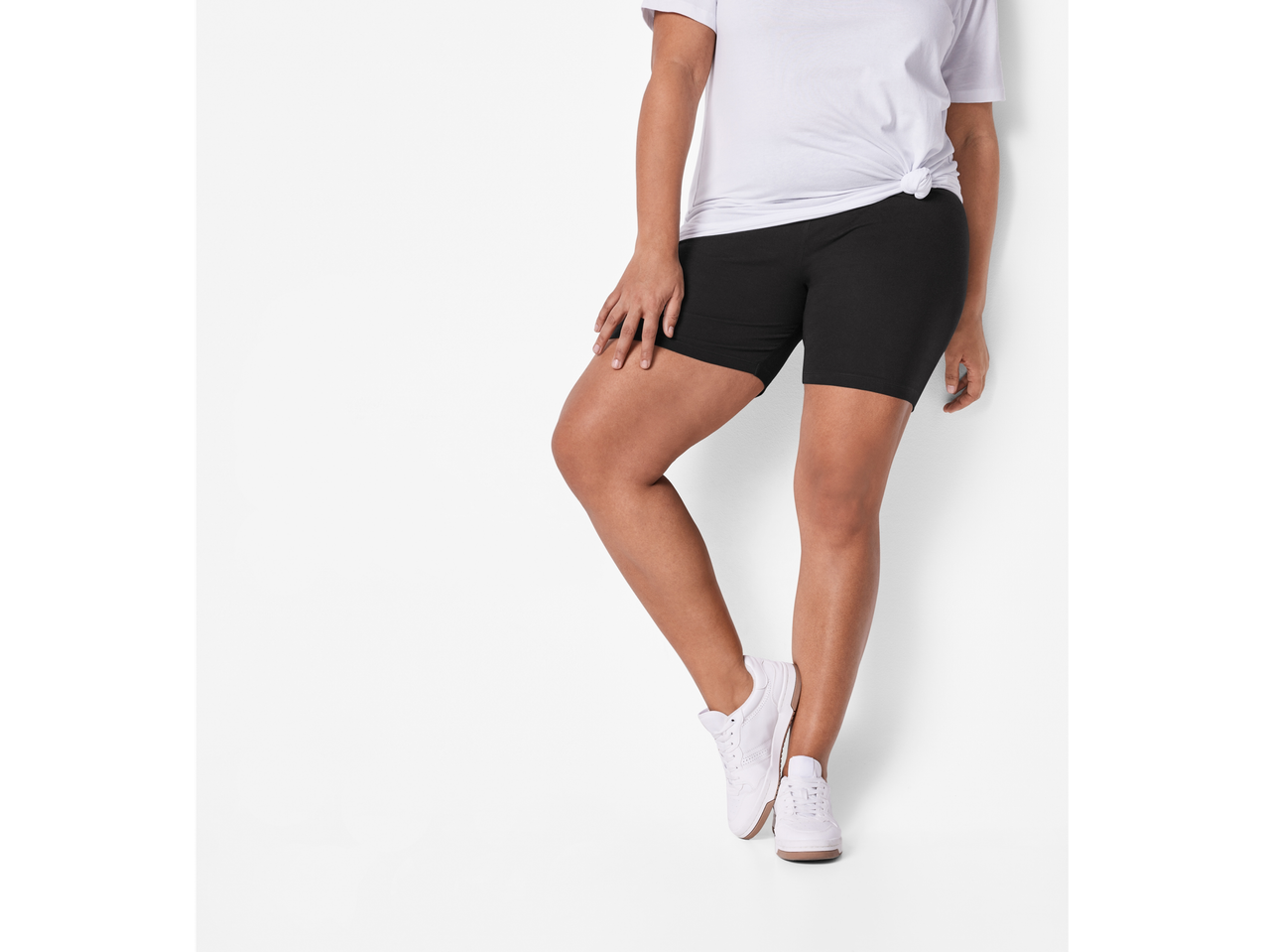 Femeie purtând pantaloni scurți de ciclism negri și adidași albi.