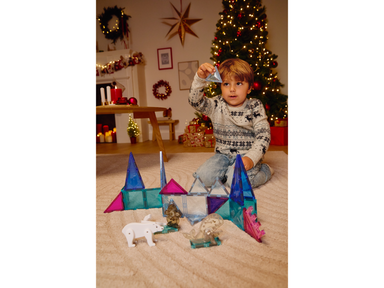 Момче играе с магнитни блокчета Lupilu в коледна обстановка.