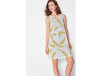 O femeie poartă o rochie de vară albă cu imprimeu abstract verde-măsliniu.