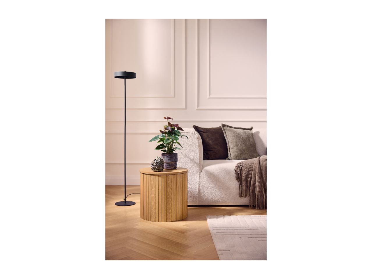 Modern living room with a wooden side table, a white sofa, and a black floor lamp.