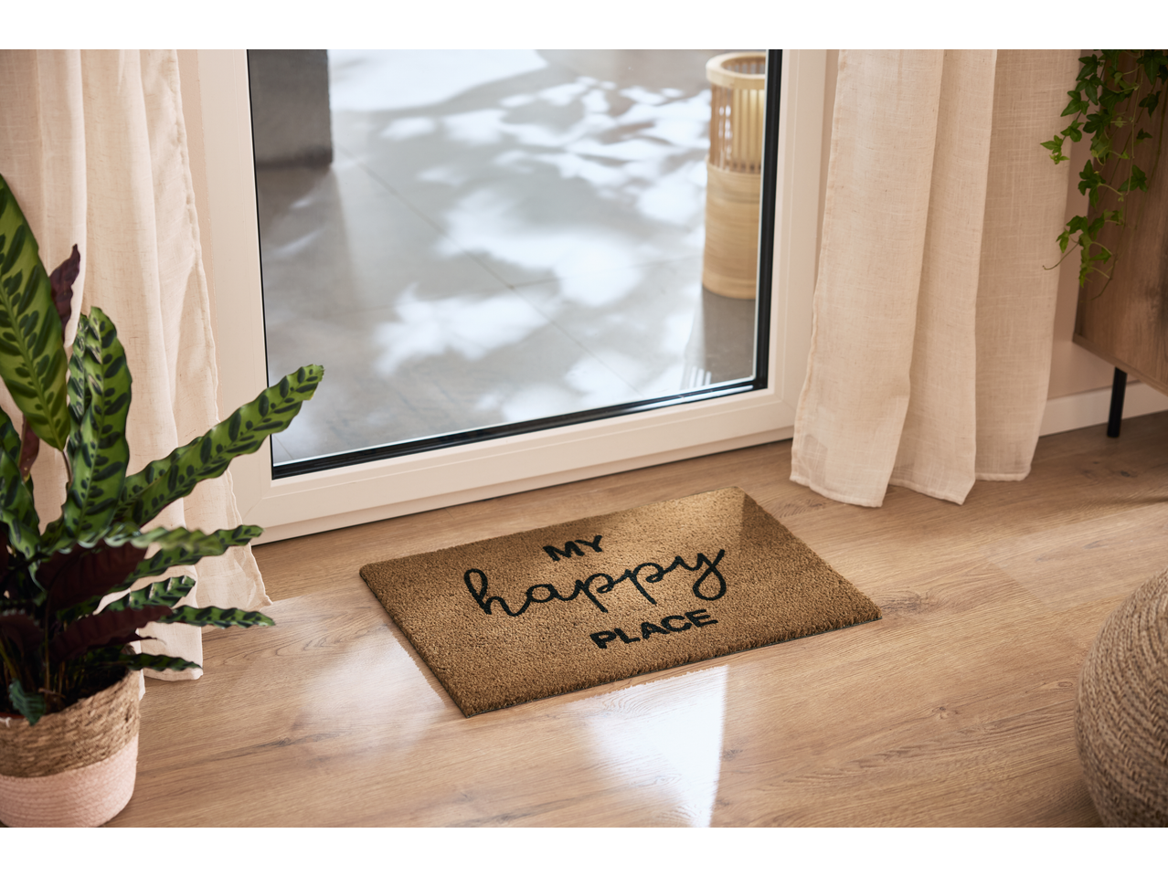 Felicidade à porta: capacho com texto 'MY happy PLACE' e plantas verdes.