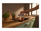 A copper pot with a lid on an induction hob in a modern kitchen.