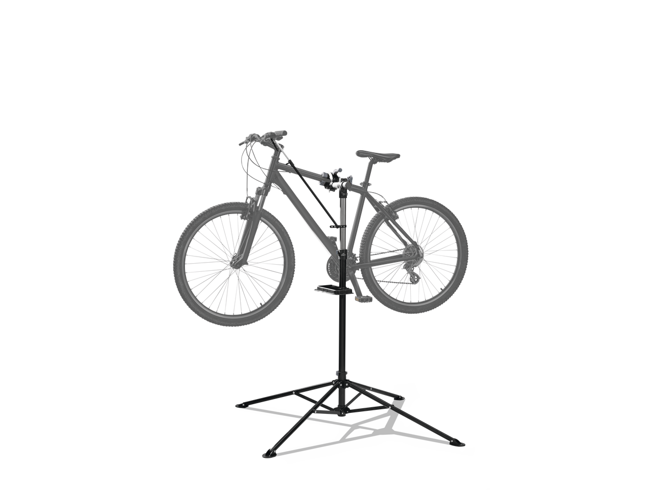 A bicycle mounted on a black repair stand with a tool tray, against a black background.
