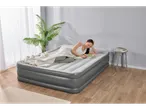 A woman relaxes on a gray Intex air mattress, reading a book.