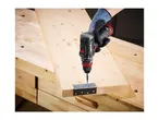 A person using a Parkside cordless drill to attach a hinge to a wooden board on a workbench.