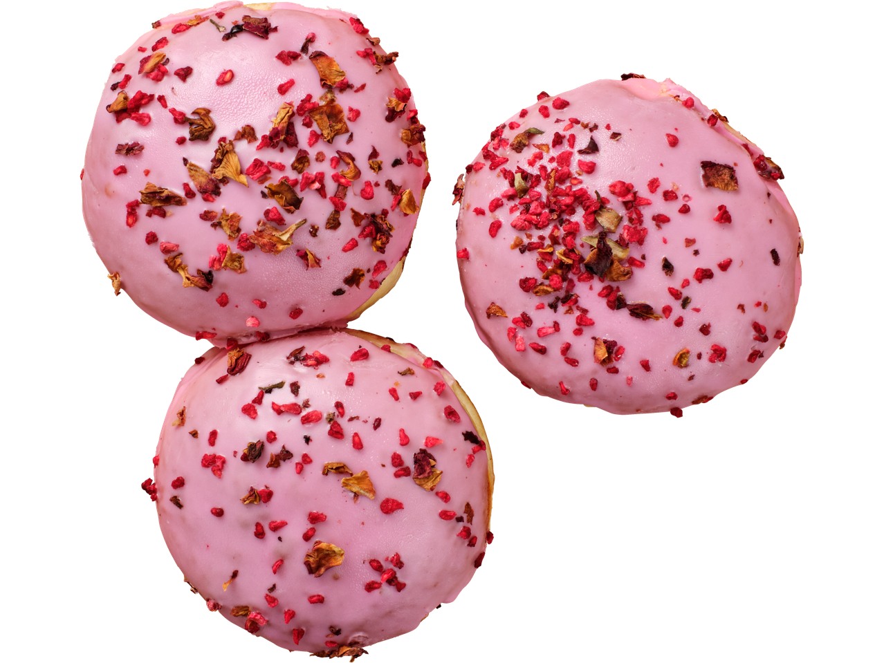 Trīs rozā virtuļi ar kaltētām avenēm un rožu ziedlapiņām uz melna fona.