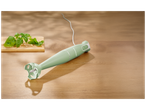 Mixeur plongeant vert sur une table en bois avec du basilic et du parmesan.