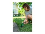 Woman trimming grass edge with a cordless grass shear in a garden.