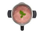 Overhead view of a blender with a pink smoothie garnished with mint leaves.