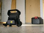 A Parkside work light illuminates a concrete floor in a workshop, near a tool case.