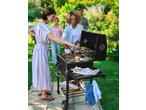 GRILLMEISTER Holzkohle-Grill com costelas e vegetais, com pessoas sorridentes num jardim.
