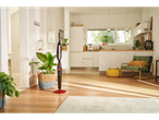 A steam mop stands on a wooden floor in a modern kitchen and living area.