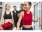 Femei părăsesc o sală de sport îmbrăcate în haine de sport și purtând saltele de yoga.
