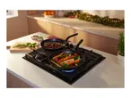Two frying pans with food on a gas hob in a kitchen decorated for Christmas.
