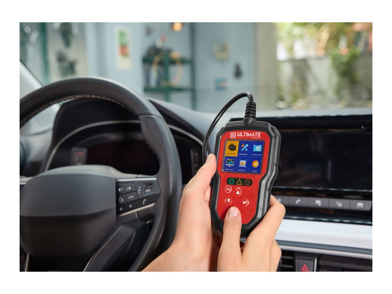 A person using a car diagnostic tool inside a vehicle, with the steering wheel visible.