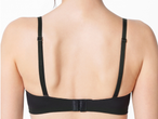Гръб на жена, носеща черен сутиен с регулируеми презрамки и закопчалка.