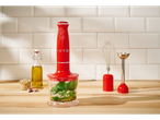 Blender de mână roșu Silvercrest® 3 în 1 cu accesorii, pregătind pesto pe un blat de lemn.