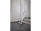 A silver multi-purpose ladder with green accents, set up on a tiled floor next to stairs.