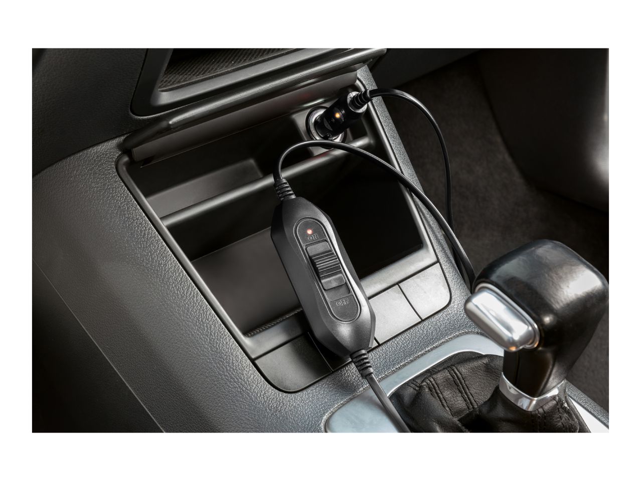 Car charger with an on/off switch and indicator light plugged into a car's console