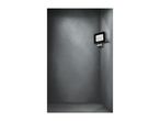 A black LED floodlight with a motion sensor mounted on a gray concrete wall.