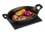 Grilled steak with red onion and bell pepper in a black cast iron pan on a slate board.