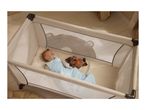 Baby sleeping in a playpen with a pacifier and a glowing plush toy.