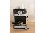 Espressor negru și argintiu cu cești albe și cafea măcinată într-un portafiltru.