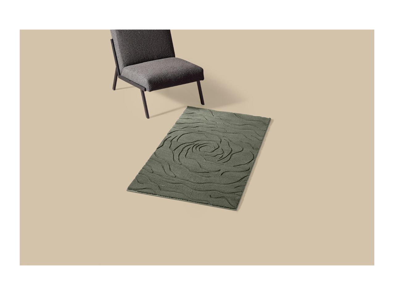 A green bath mat with a rose pattern next to a grey armchair
