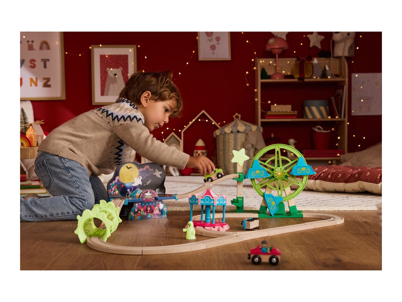 A child plays with a wooden train set featuring a Ferris wheel and carousel.