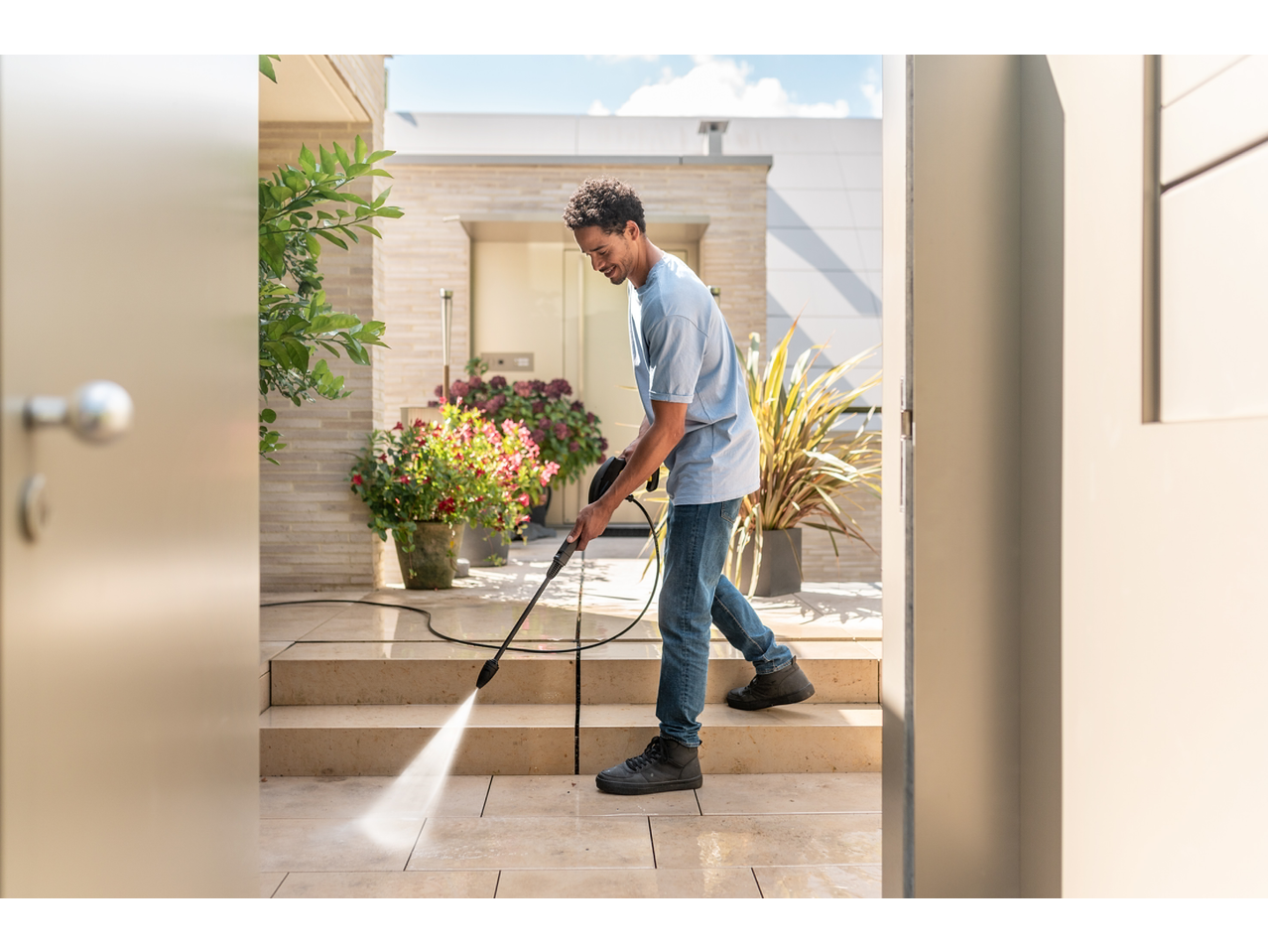 Bărbat curăță o terasă cu un aparat de spălat cu presiune KÄRCHER KHD3.