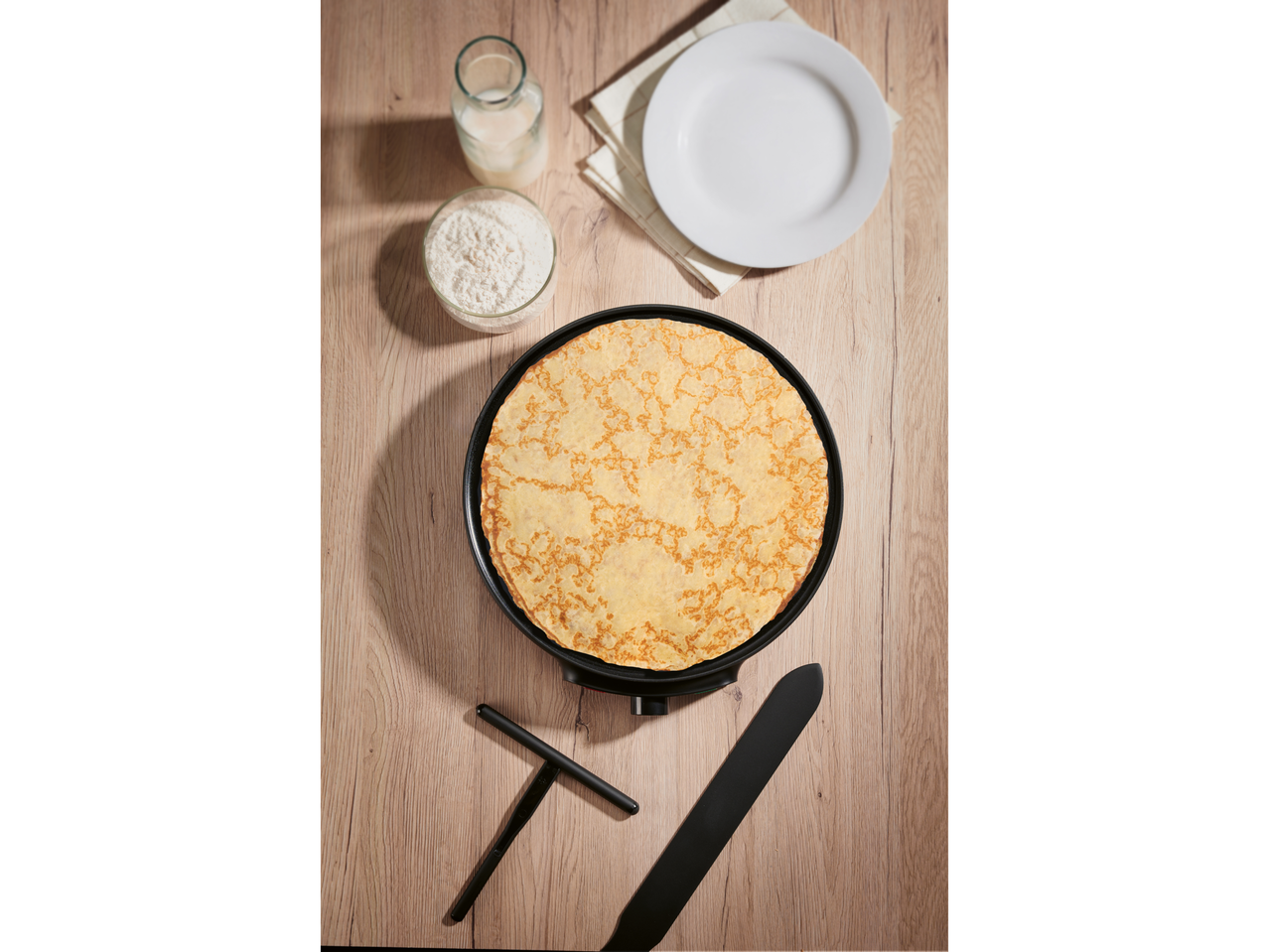 SILVERCREST® Crêpe Maker sa palačinkom, brašnom i mlekom na drvenom stolu.
