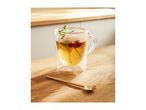 Glass mug with tea, mint, and cherries on a wooden table with a golden spoon.