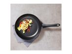 Overhead view of a black frying pan with cooked chicken and vegetables.