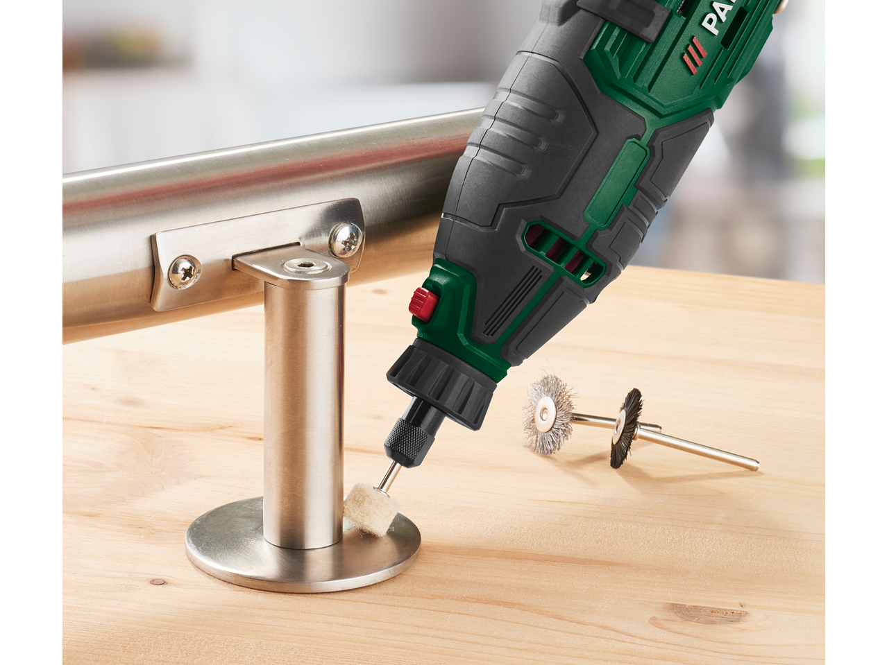 A rotary tool with a polishing attachment is used on a metal railing, with wire brushes nearby.