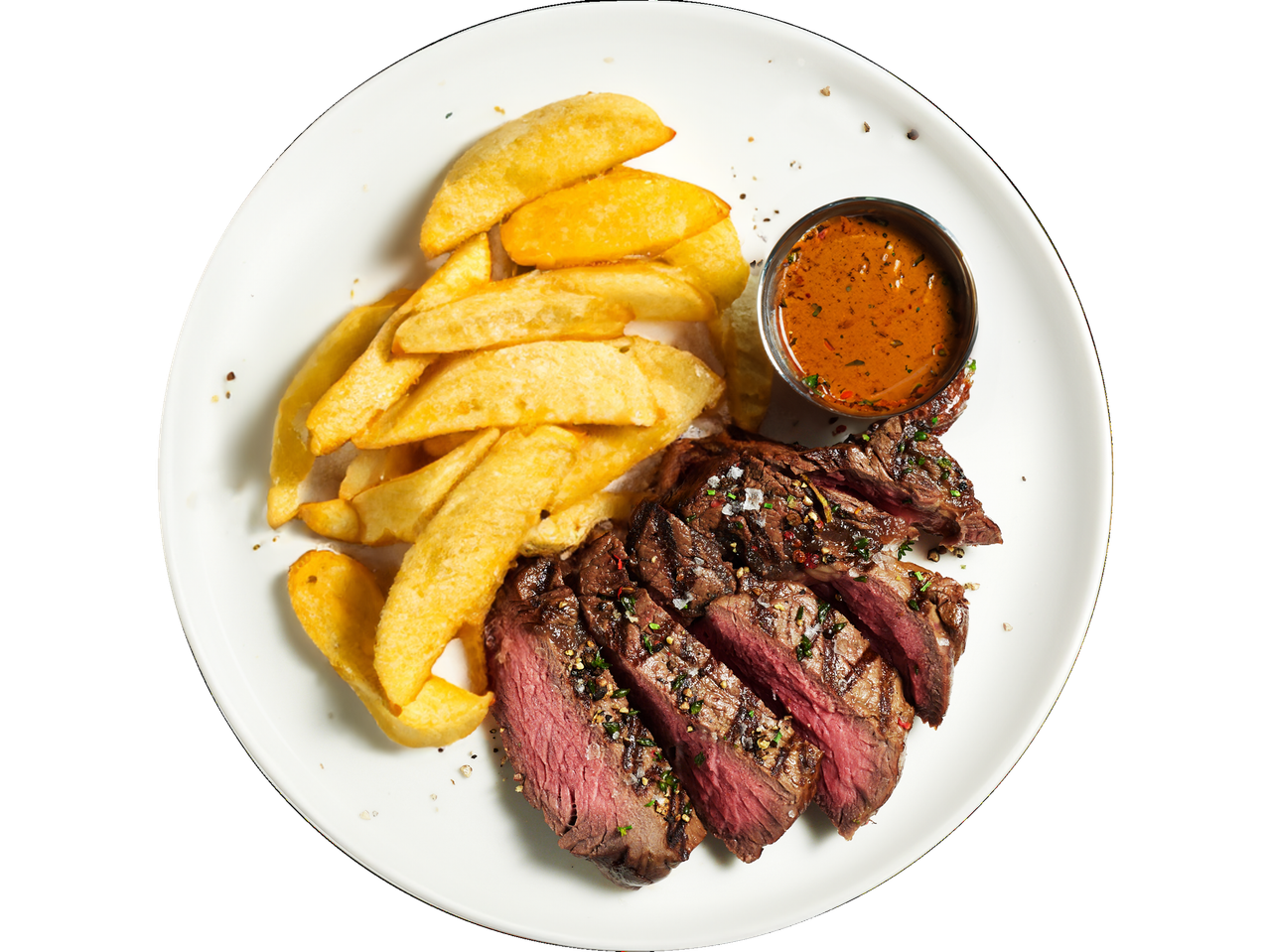 Sliced grilled steak served with potato wedges and a side of sauce.