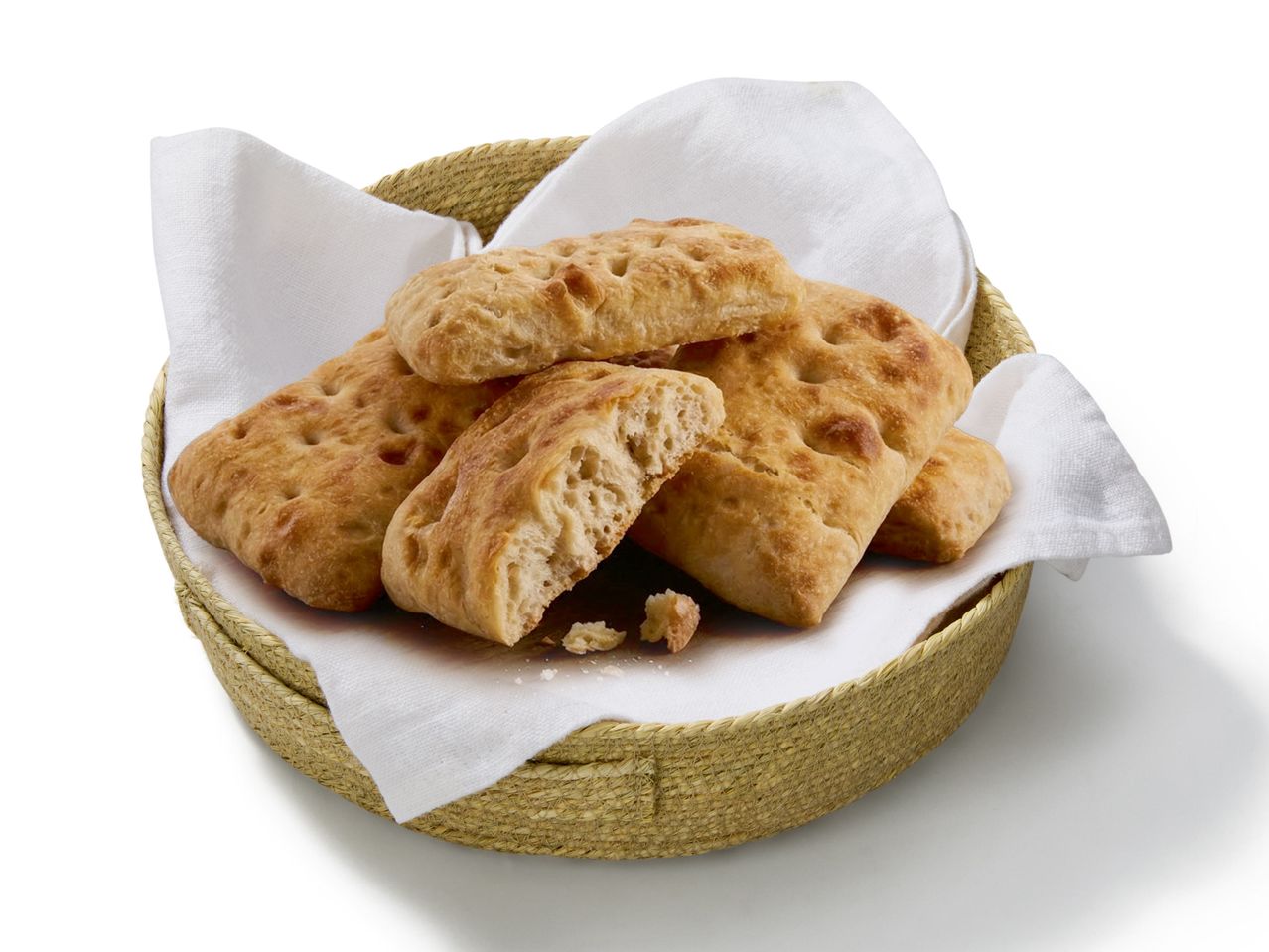 Pâine focaccia proaspăt coaptă într-un coș de pâine, pe un șervet alb.