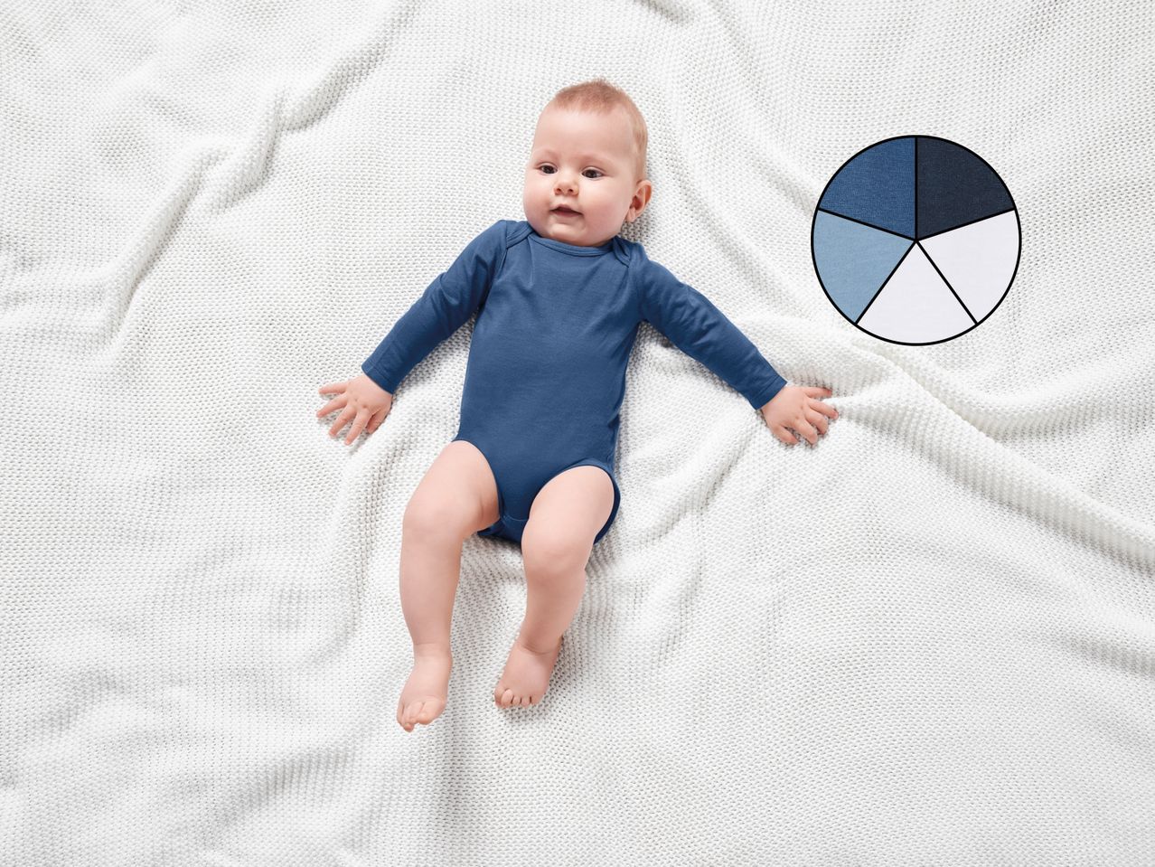 A baby in a blue bodysuit lying on a white knitted blanket, with a color palette.