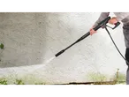 Uma pessoa limpa uma parede com uma lavadora de alta pressão Parkside® Hochdruckreiniger, removendo verdete.
