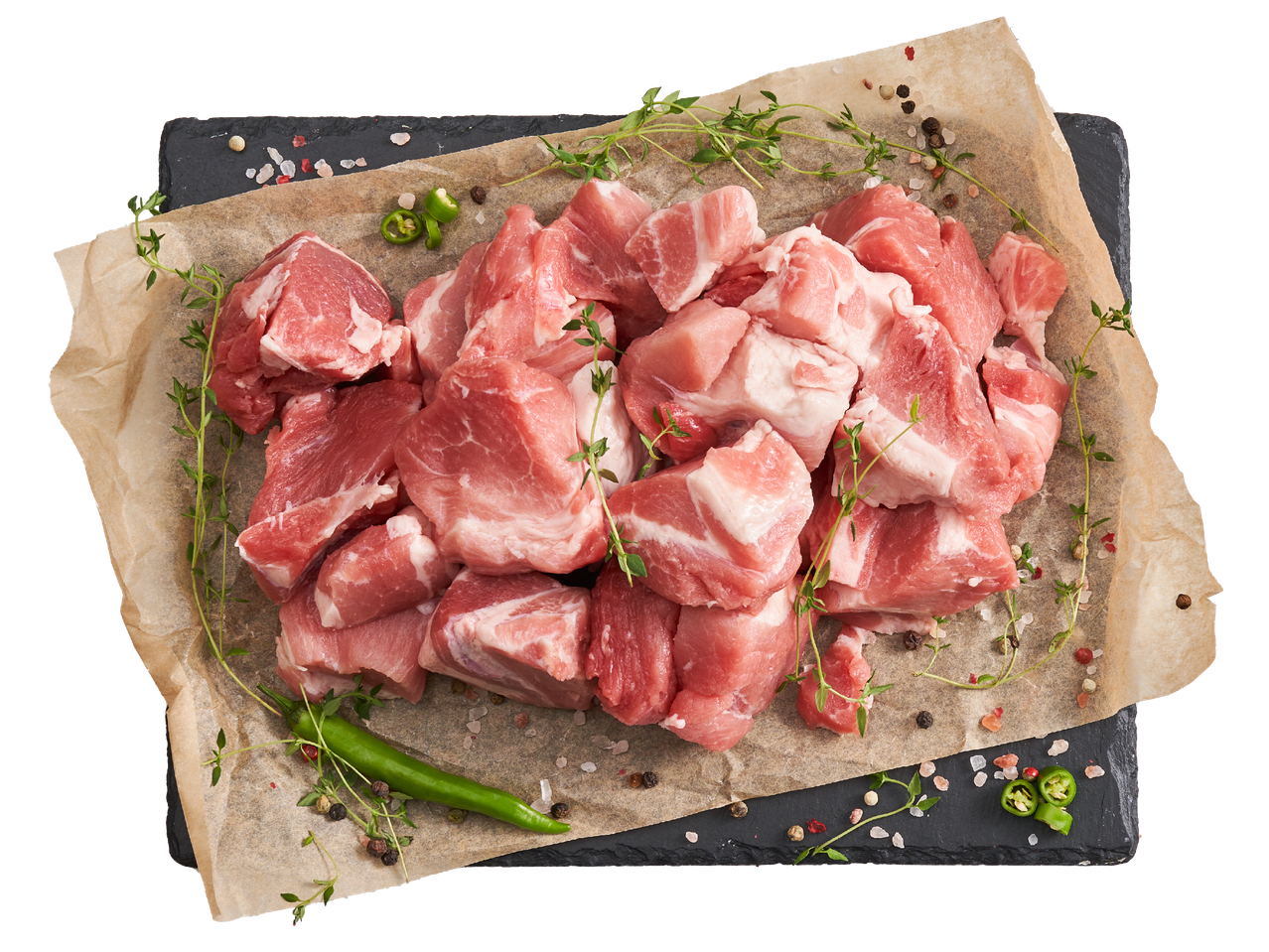 Сурово свинско месо на кубчета с мащерка, люти чушки и подправки върху хартия за печене.