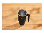 Black and gold travel mug with a handle on a wooden table.