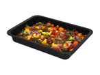 Black roasting pan filled with roasted gnocchi, cherry tomatoes, red onion, and herbs.