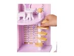 A child's hand interacting with a pink wooden dollhouse, featuring miniature furniture and a spiral staircase.