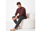 Man in red and grey plaid pajamas sitting on a white textured chair.