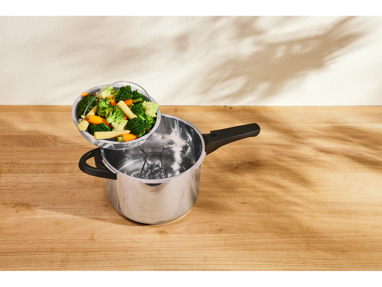 Panela de pressão SILVERCREST com cesto a vapor cheio de brócolos, cenouras e milho baby.