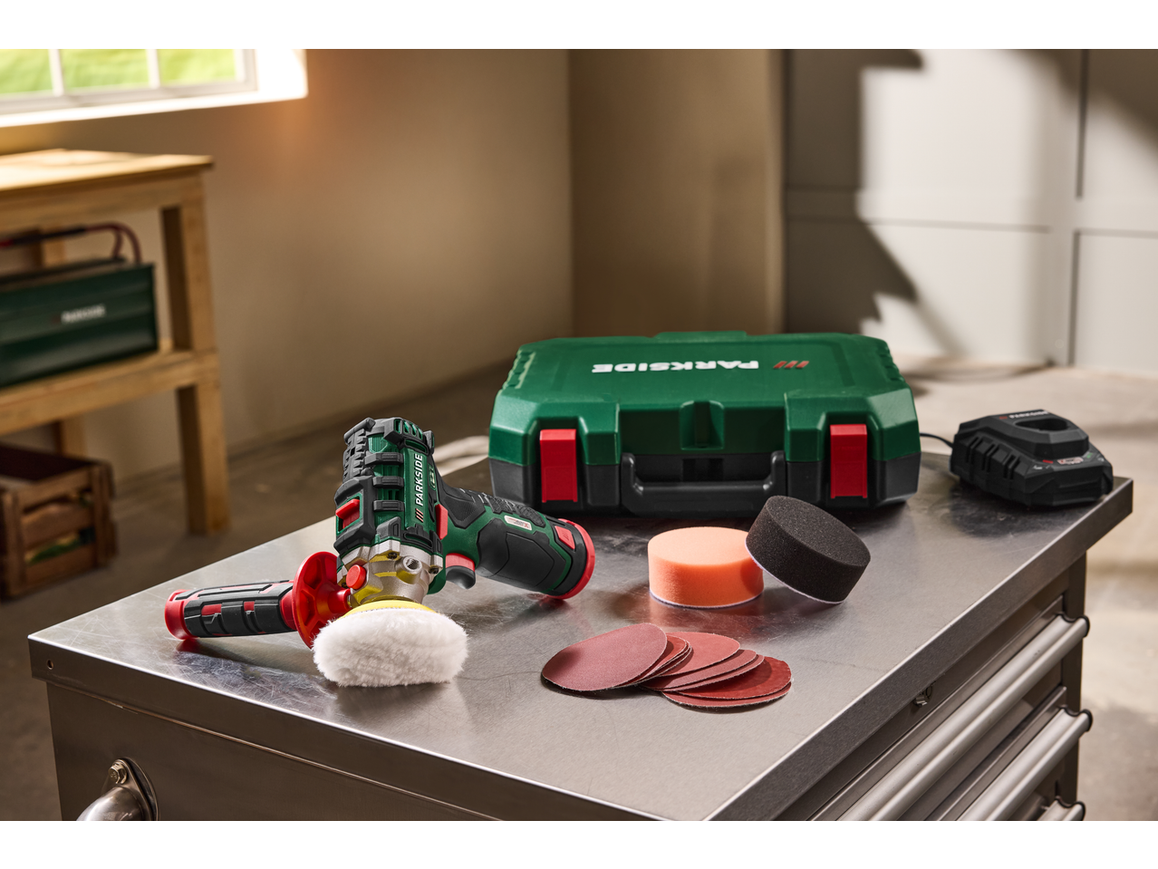 PARKSIDE® 12V Cordless Polisher/Sander with accessories on a metal workbench.