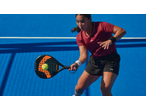Mulher a jogar padel com raquete e bola num campo azul.