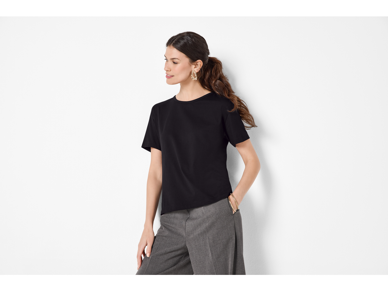 Žena u crnoj ESMARA majici od organskog pamuka i sivim hlačama.