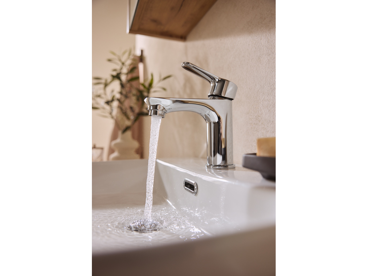 Livarno Mixer Tap with running water in a bathroom sink, with a plant in the background.
