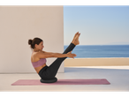 Woman in CRIVIT sports leggings and sports bra, doing yoga on a mat.