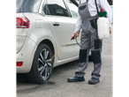 Man in Parkside® work overalls spraying a car wheel with a sprayer.